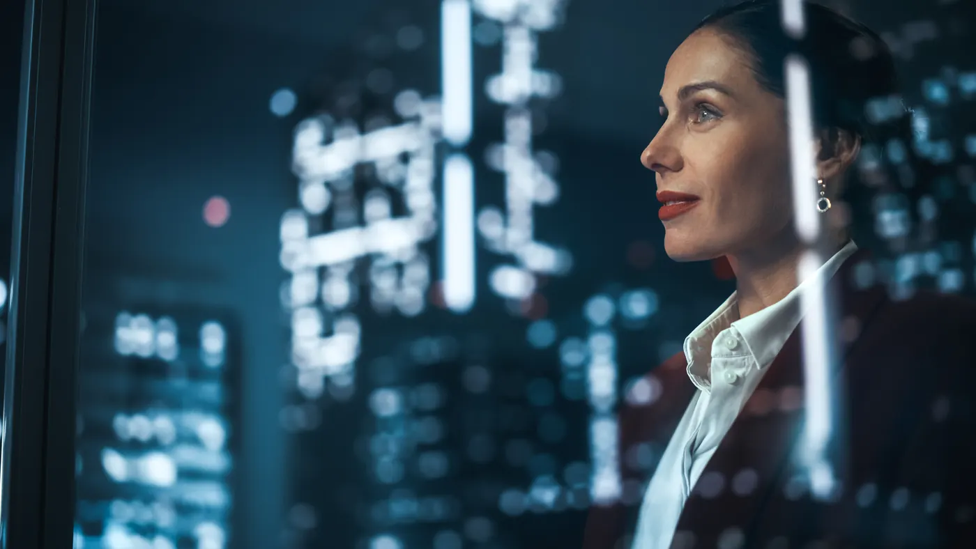 A professional woman looking out over the city lights at night
